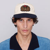 Male model Andrew Beige wearing hat with tombolo blue polo