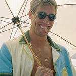 Male model wearing shirt unbuttoned smiling while holding a parasol