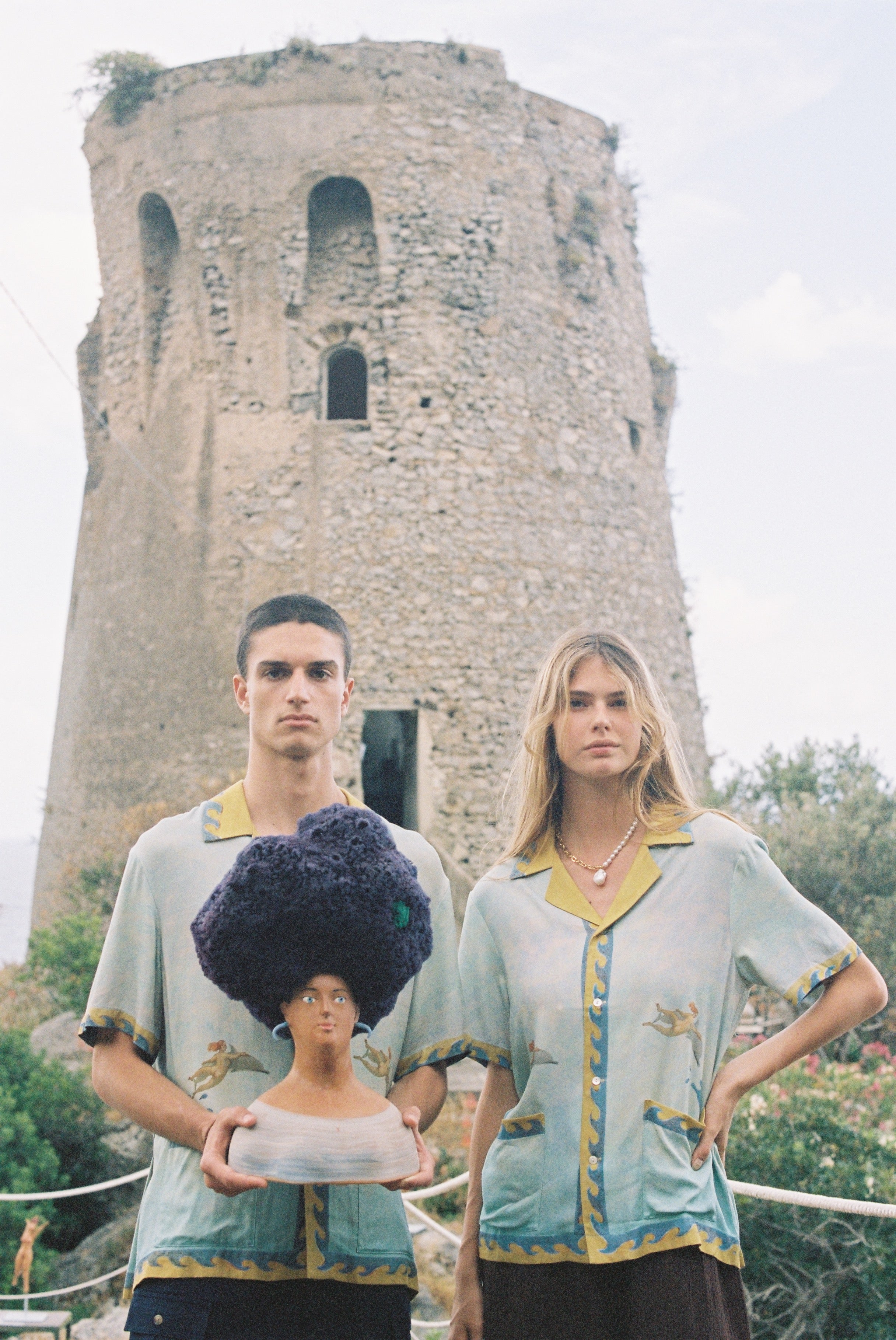 Male and female models wearing the shirt holding a Sandulli coral head statue