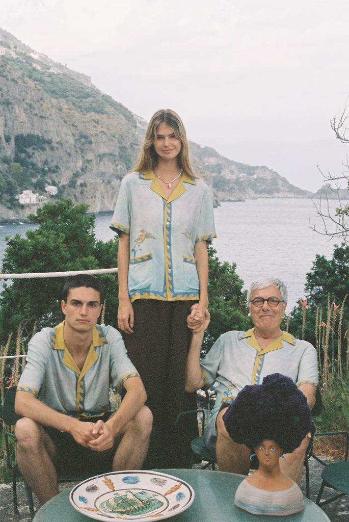 Paolo Sandulli outdoors sitting alongside a male and female model, all three wearing the shirt