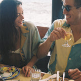 A male and female model dine together while he dons the limoncello shirt and she wears the paolo sandulli collab