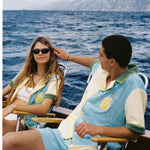 Male and female models wearing the limoncello set lounging in chairs on a boat