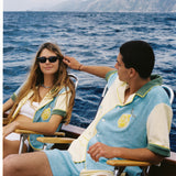 Male and female models wearing the limoncello set lounging in chairs on a boat