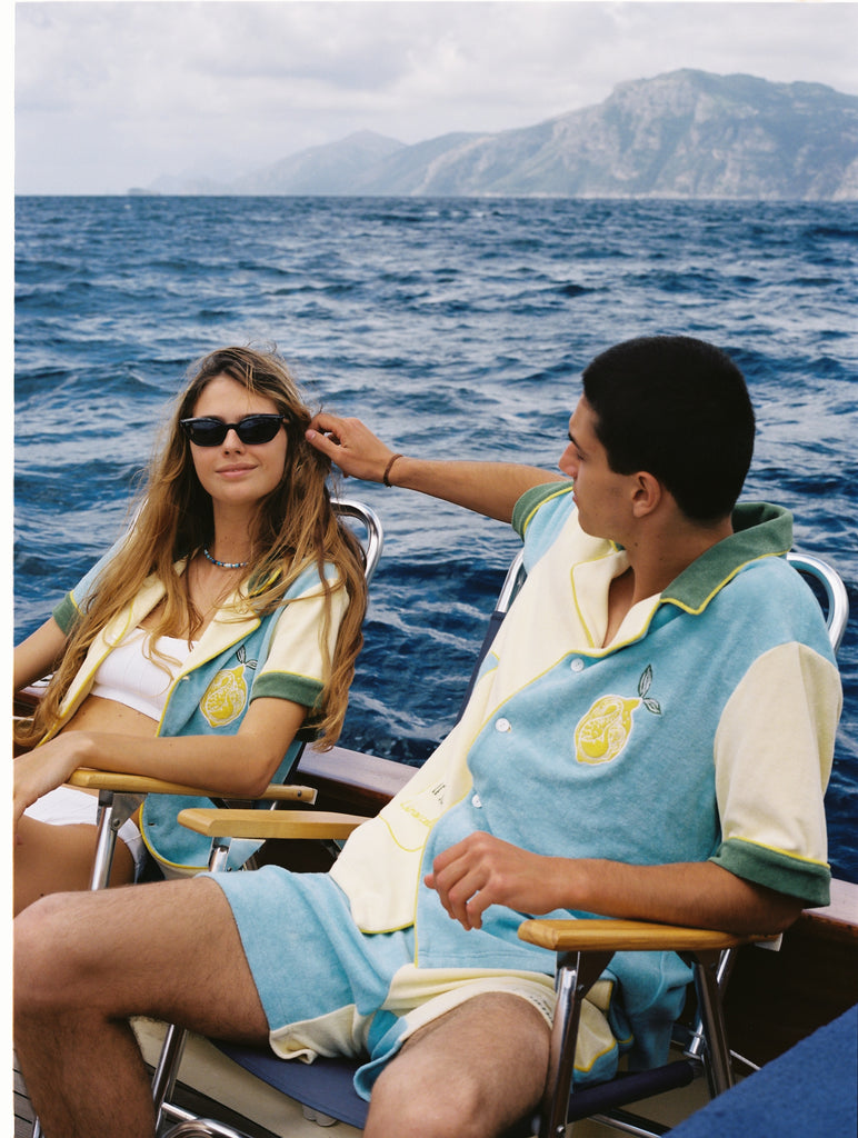 Male and female models wearing the limoncello set lounging in chairs on a boat