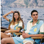Male and female models sit in chairs on boat donning the limoncello set