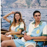 Male and female models sit in chairs on boat donning the limoncello set