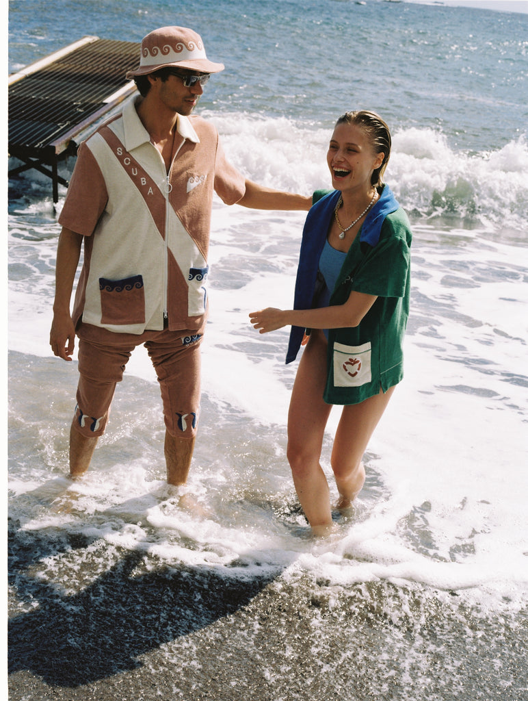 Man and woman laugh and walk through the ocean