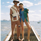 Male model wearing full set with arm around female model wearing water sport cabana
