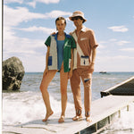 Female model in the cabana next to a male model on the beach