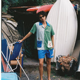 Male model in full water sport set leaning his left arm on a beach chair