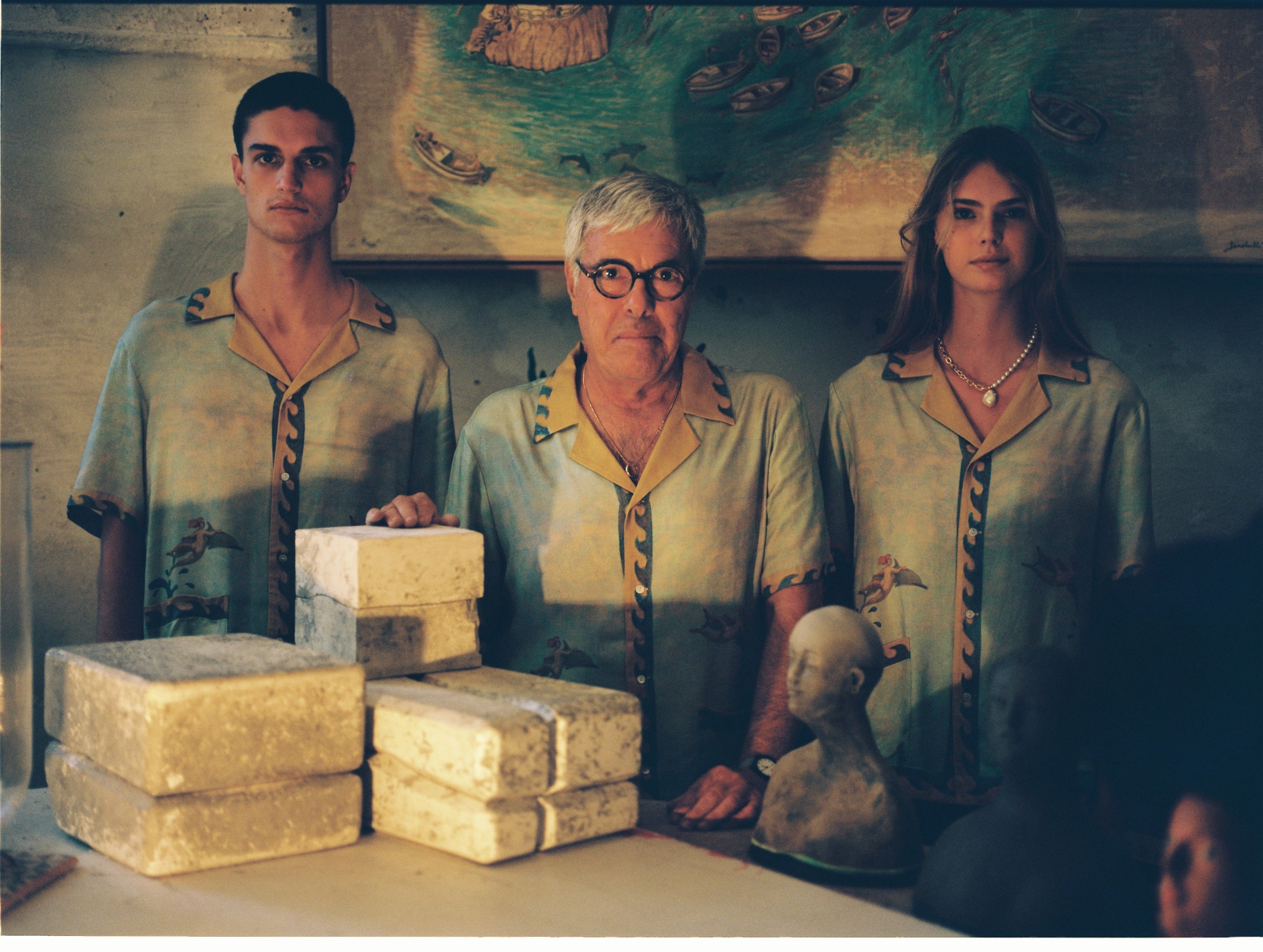 Paolo Sandulli alongside a male and female model, all three wearing the shirt dimly lit indoors