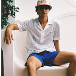 Male model wearing hat sitting on white bench