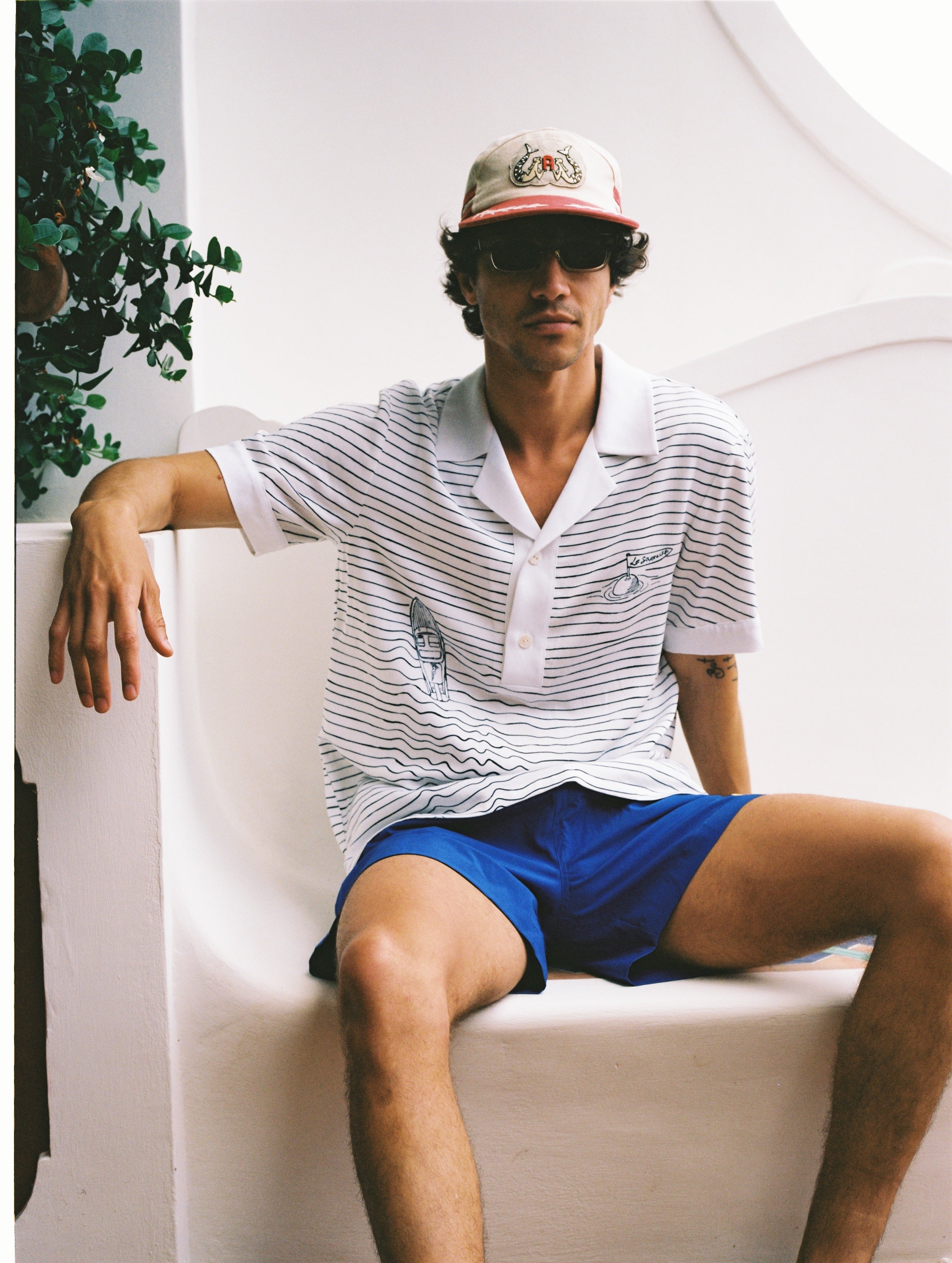 Male model wearing hat sitting on white bench