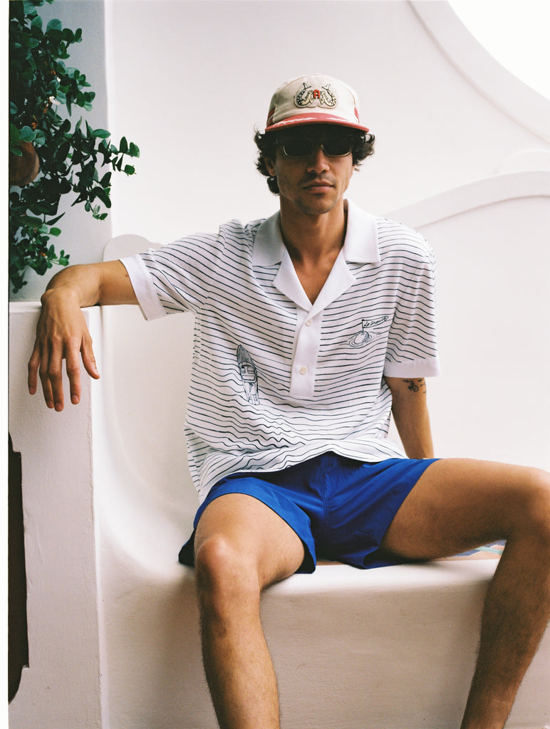 Male model wearing hat sitting on white bench