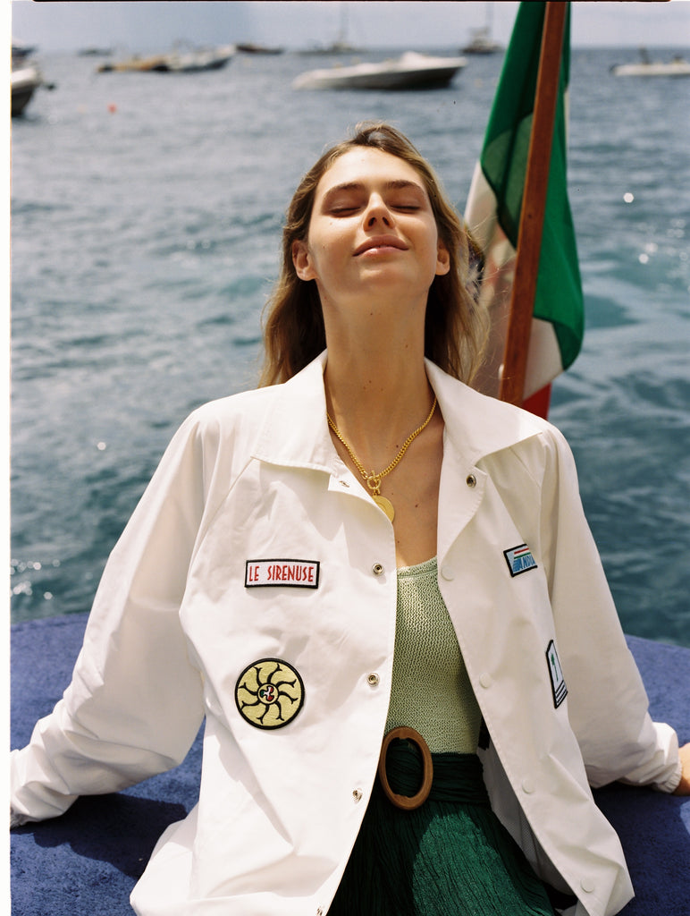 Female model wearing jacket open over swimsuit and green shorts
