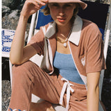 Female model in full set sitting in beach chair holding hand on hat