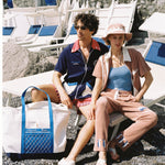 male model and female model sitting with tote bag on ground next to them