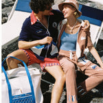 male model holding a female model with the tote bag on the ground between his legs