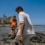 Male and female models walking along rocks at the beach in their crouching tiger cabana sets