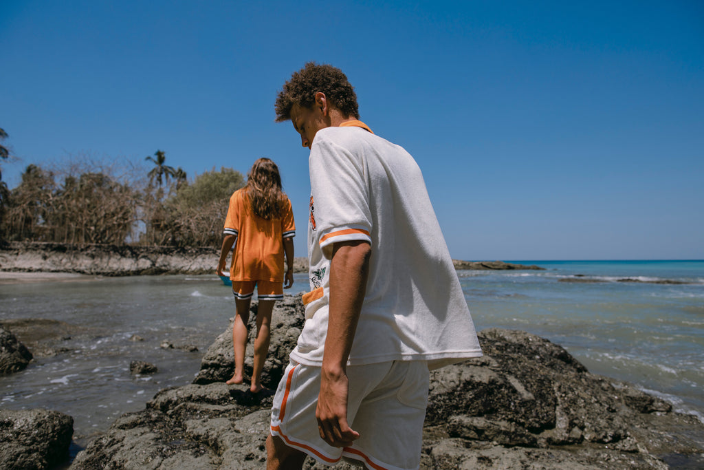Male and female models walking along rocks at the beach in their crouching tiger cabana sets