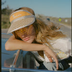 Female model leaning out of car roof wearing visor