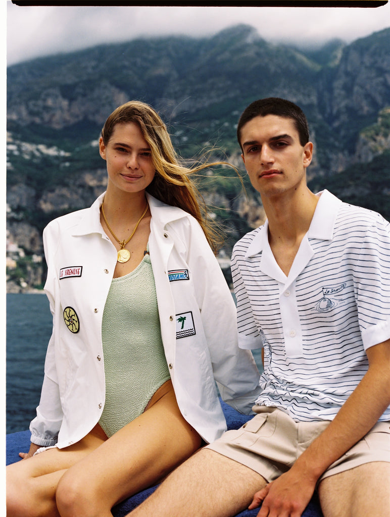 Female model wearing jacket unbuttoned over a one piece swimsuit on a boat