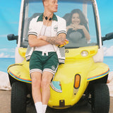 Man wears full terry cloth set and leans agaiinst Department of sanitation car while woman smiles in driver's seat