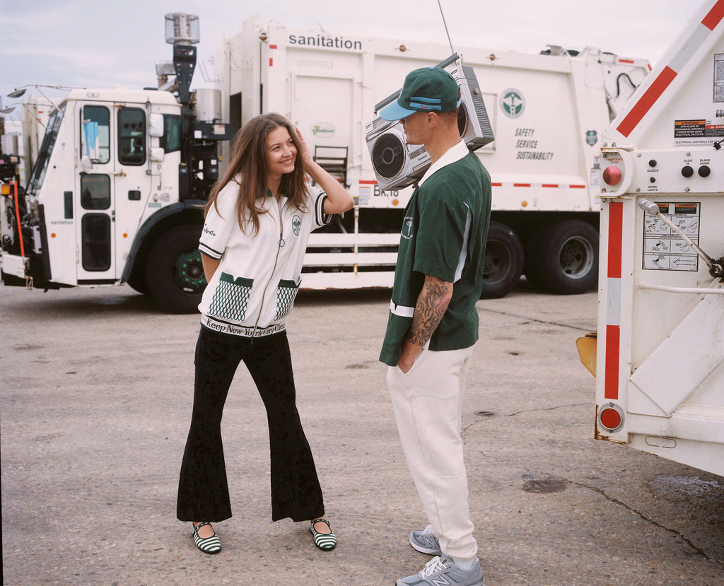 Female model smiling at male model in dsny cabana while he dons dsny hawaiian