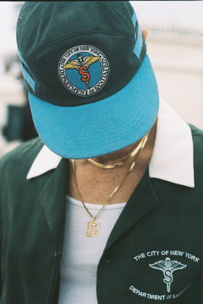 Male model looking down wearing cap with the DSNY Hawaiian