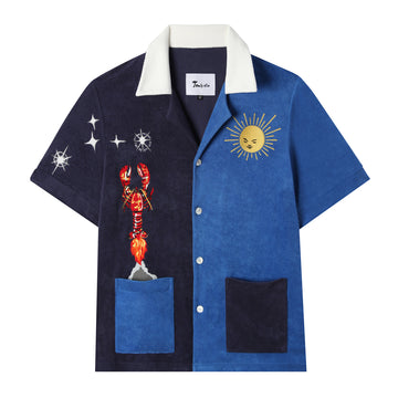 Blue and navy terrycloth tee with embroidered lobster taking off like a rocket out of the left pocket into stars with the sun looking down from the upper right side, also features a white collar and alternate navy and blue pockets