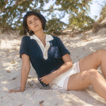 Woman sits in sand while gazing at camera 
