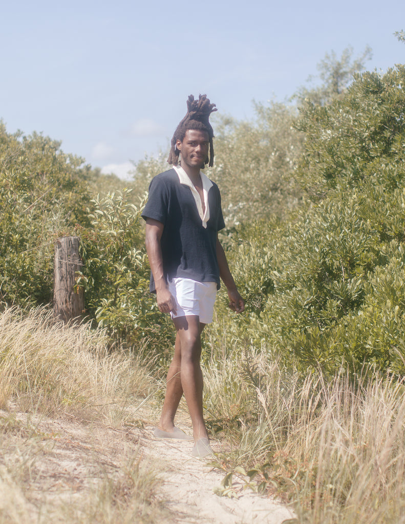 Man wearing unbuttoned polo standing in sand dune