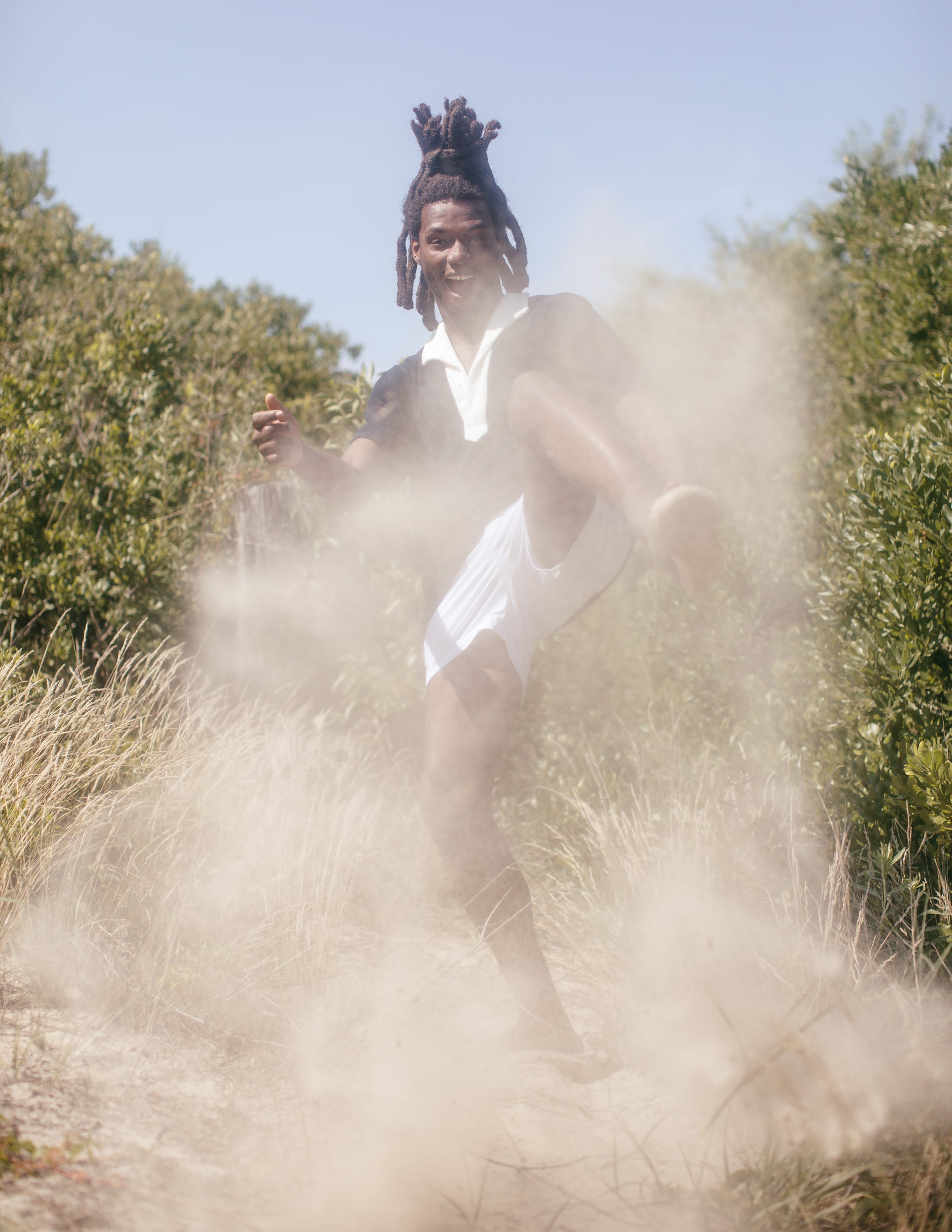 Man makes kicking motion as sand flies around the frame