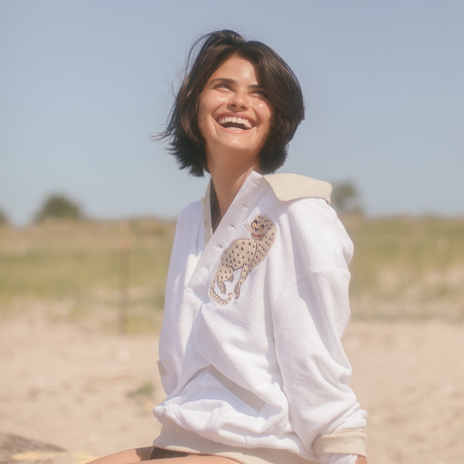 Female model smiling in the sun leopard cabana sitting on a grassy beach