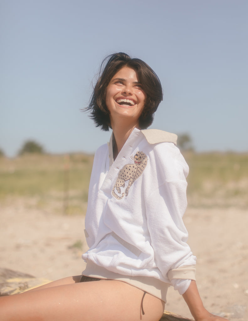 Female model smiling in the sun leopard cabana sitting on a grassy beach