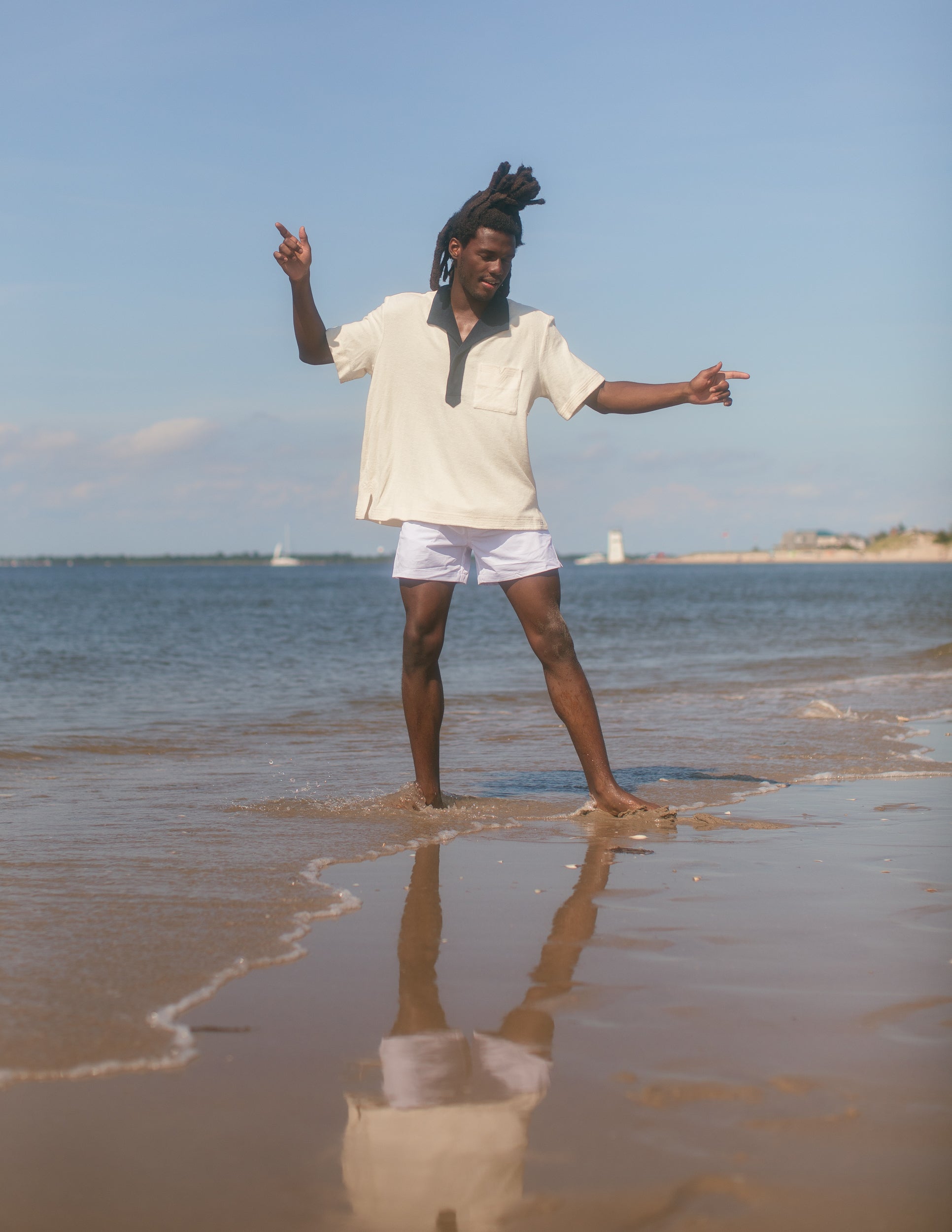 Man wearing polo while playing in the shallow water at the beach