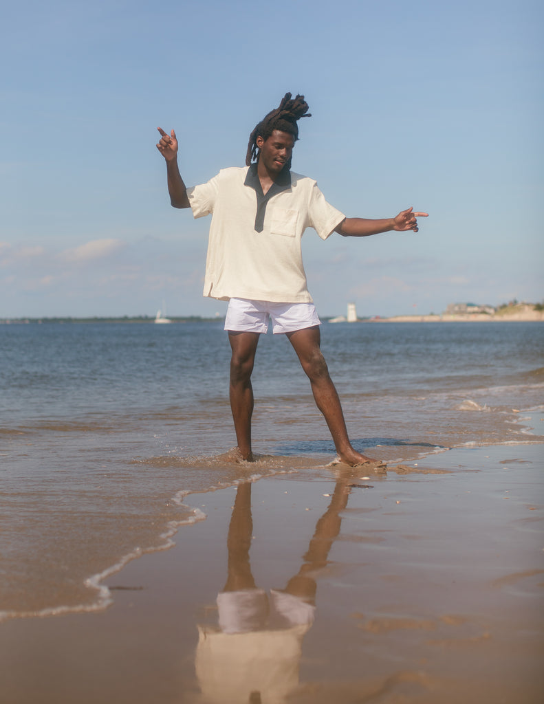 Man wearing polo while playing in the shallow water at the beach