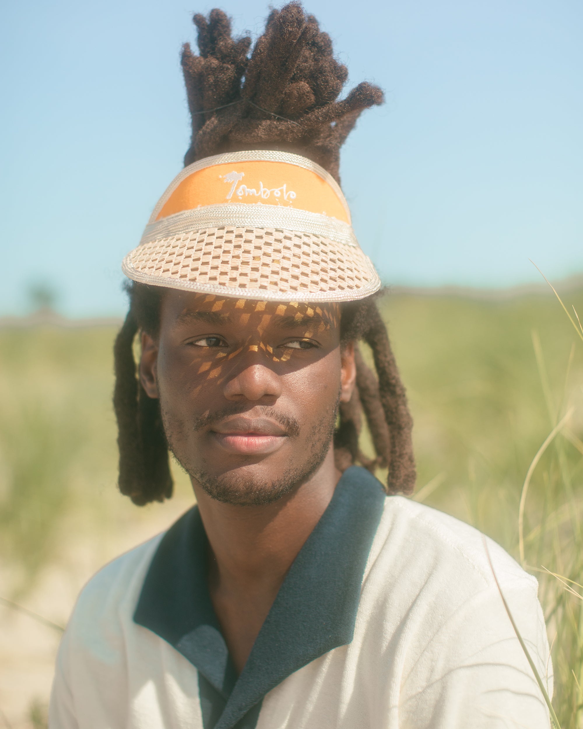 Man wearing Tombolo visor in close up shot displays the navy collar of the polo