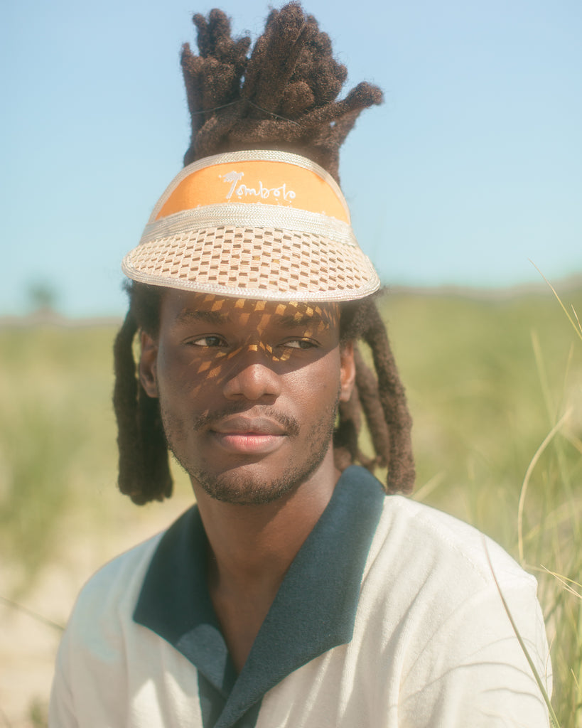 Man wearing Tombolo visor in close up shot displays the navy collar of the polo