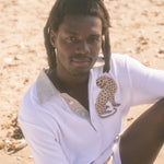 Male model wearing sun leopard cabana sitting on a sandy beach