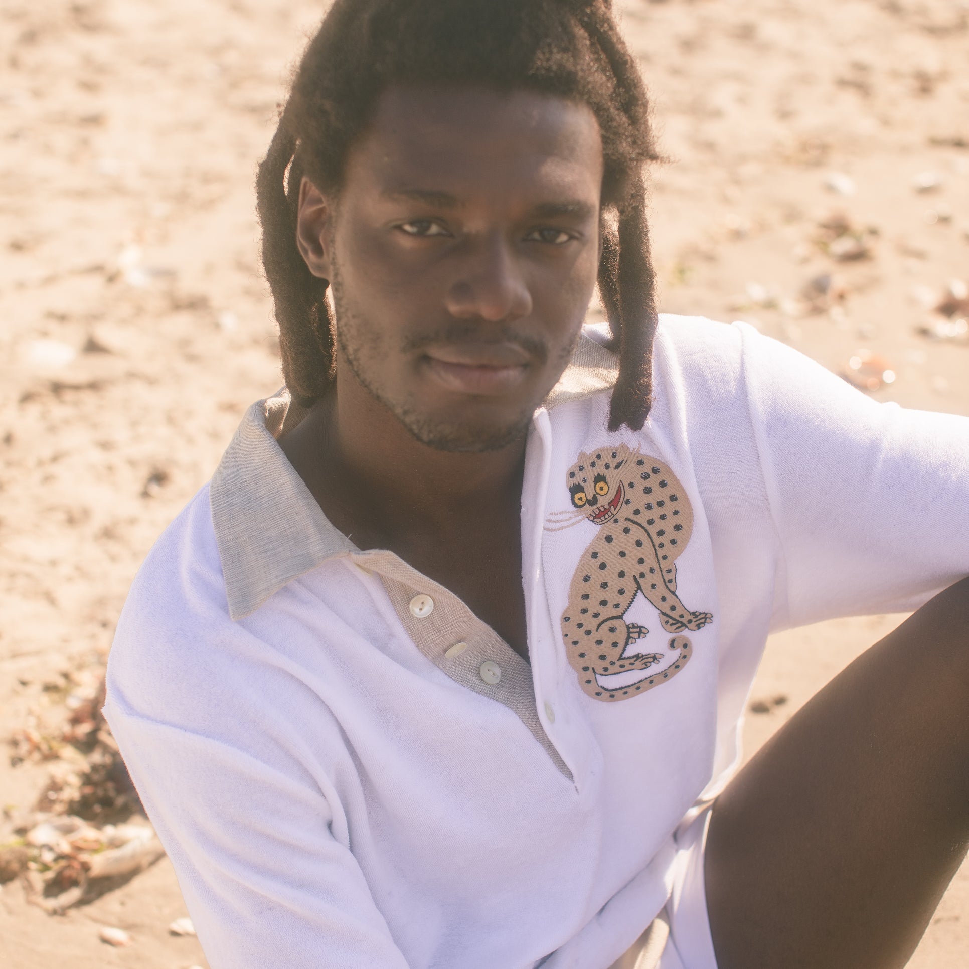 Male model wearing sun leopard cabana sitting on a sandy beach