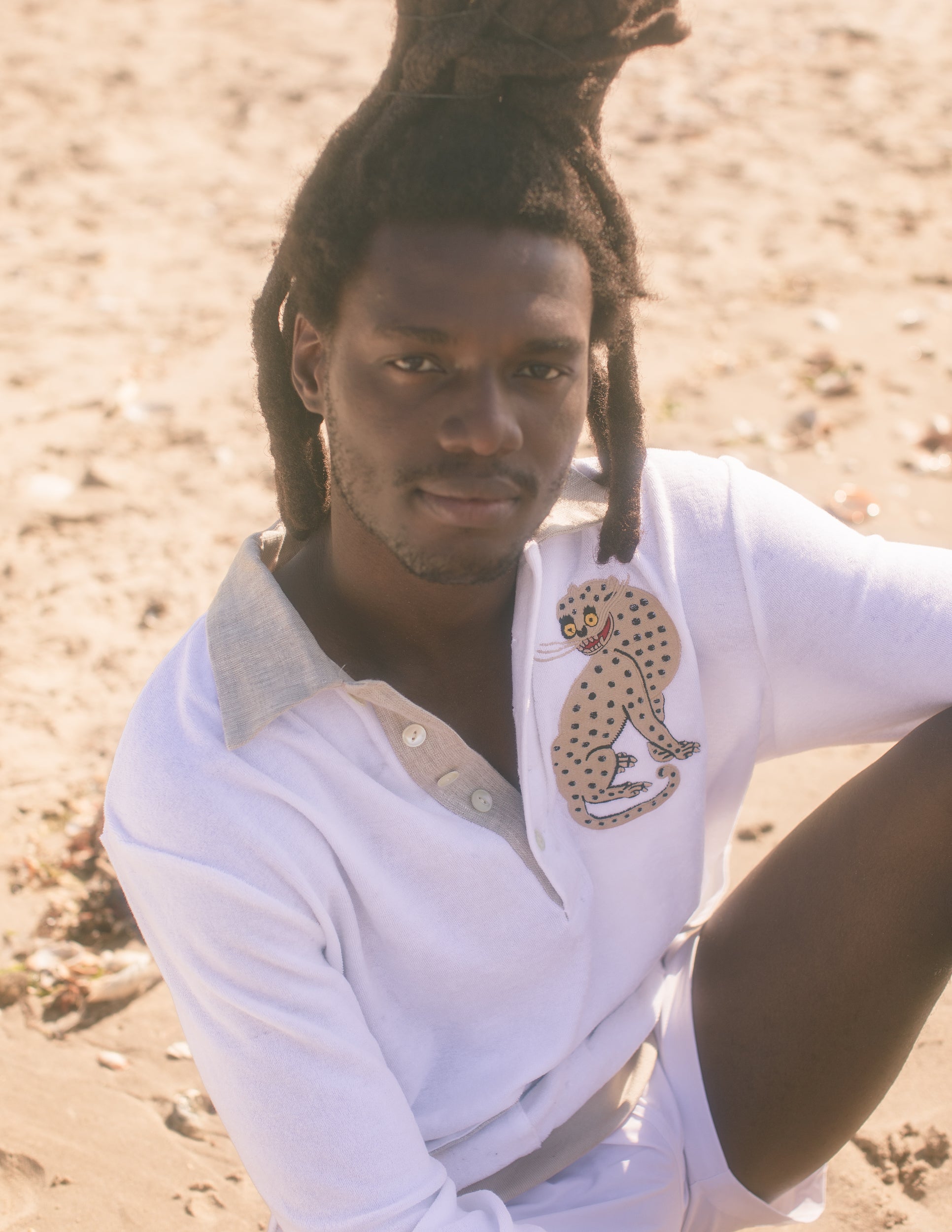 Male model wearing sun leopard cabana sitting on a sandy beach