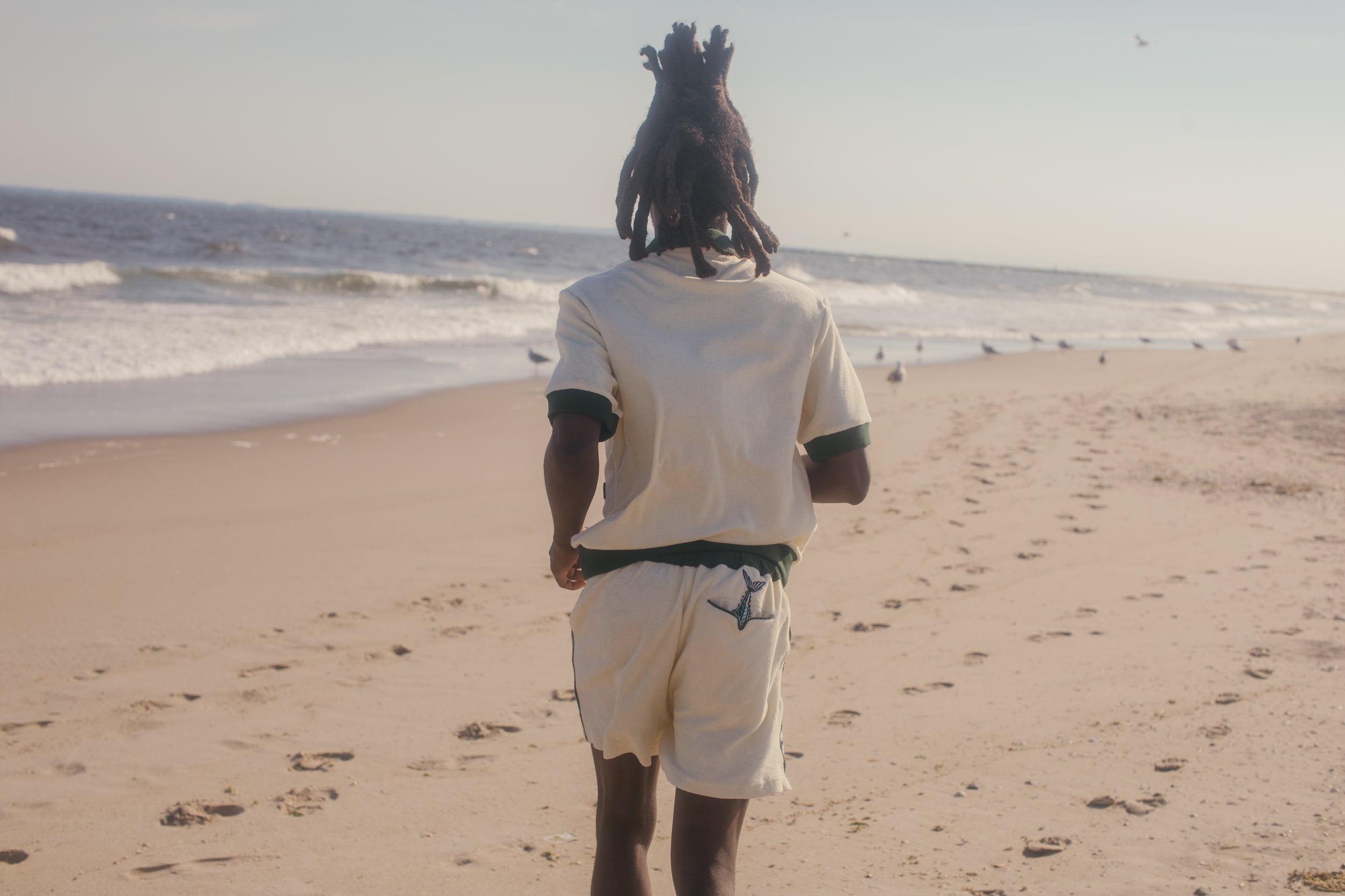 male model running on beach wearing full matching angler set