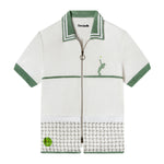 Flat lay product photo of shirt showing light green contrast collar and sleeve borders along with embroidered tennis player and ball and mesh net pockets