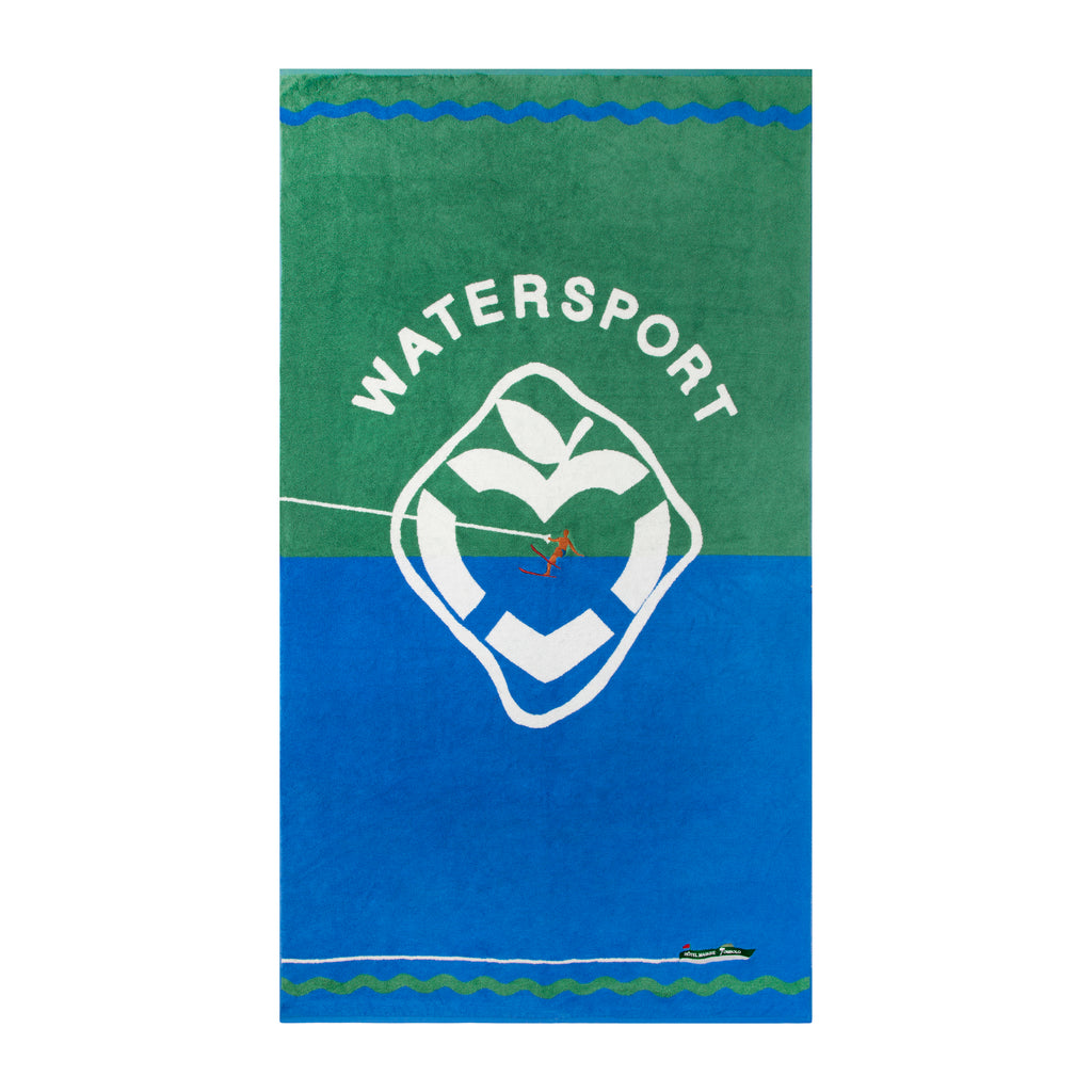 lay flat product photo of water sport towel, with top half green and bottom half blue. White water sport applique and hotel magique apple heart shaped life preserver takes up main visual space