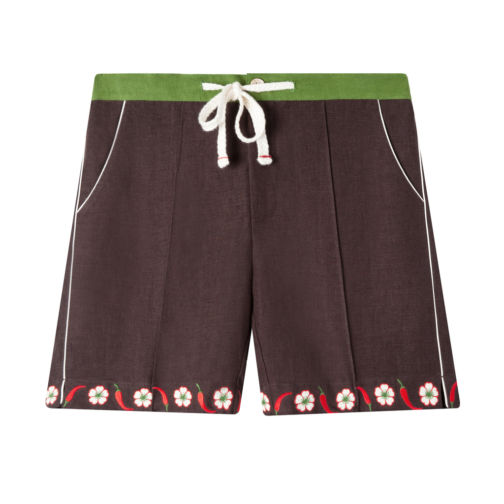 Front view of cabana shorts in brown linen with embroidered red chili peppers and white chili flowers forming a border along both leg openings. Green waistband and drawstring tied. 