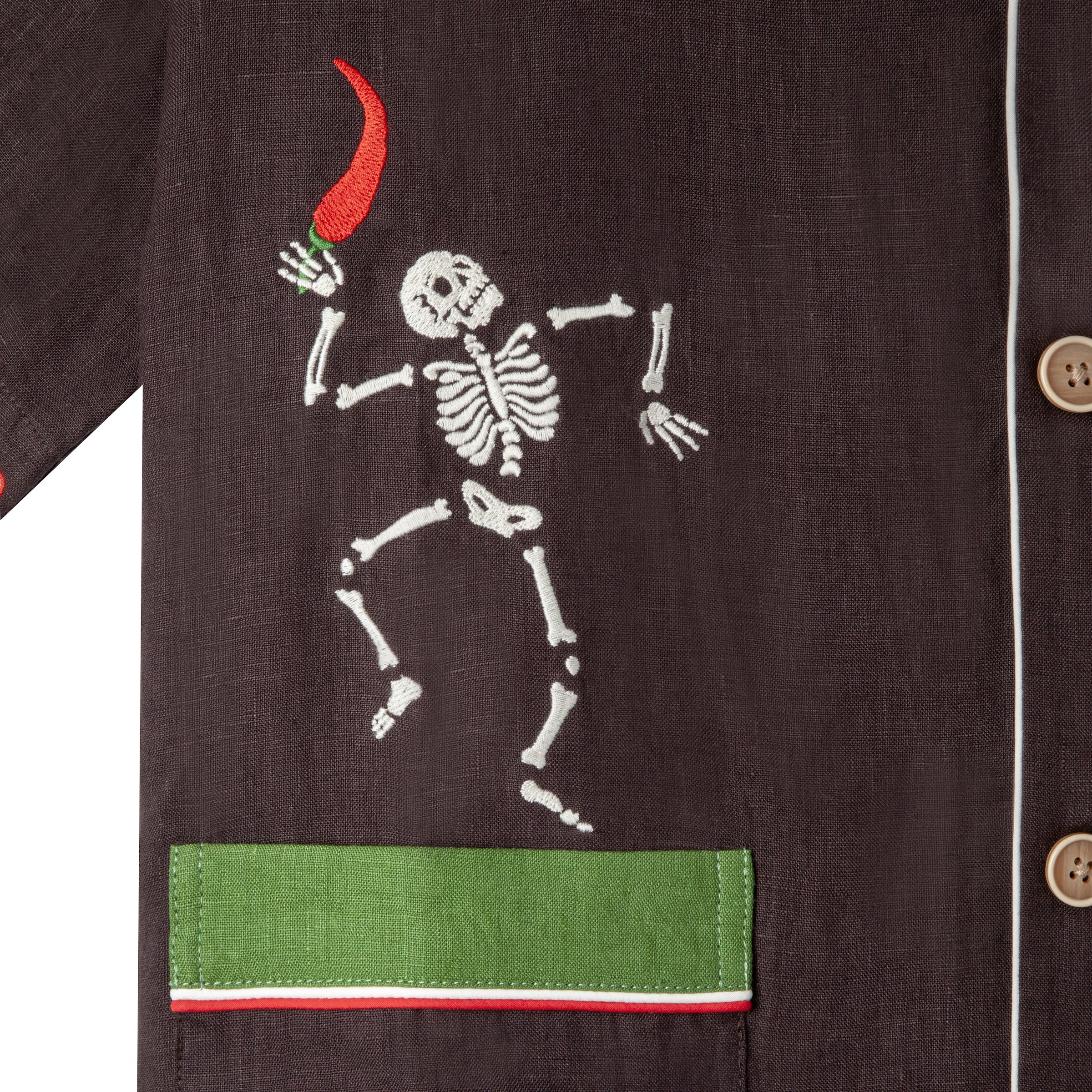 Close up view of embroidered skeleton holding a chili pepper. 