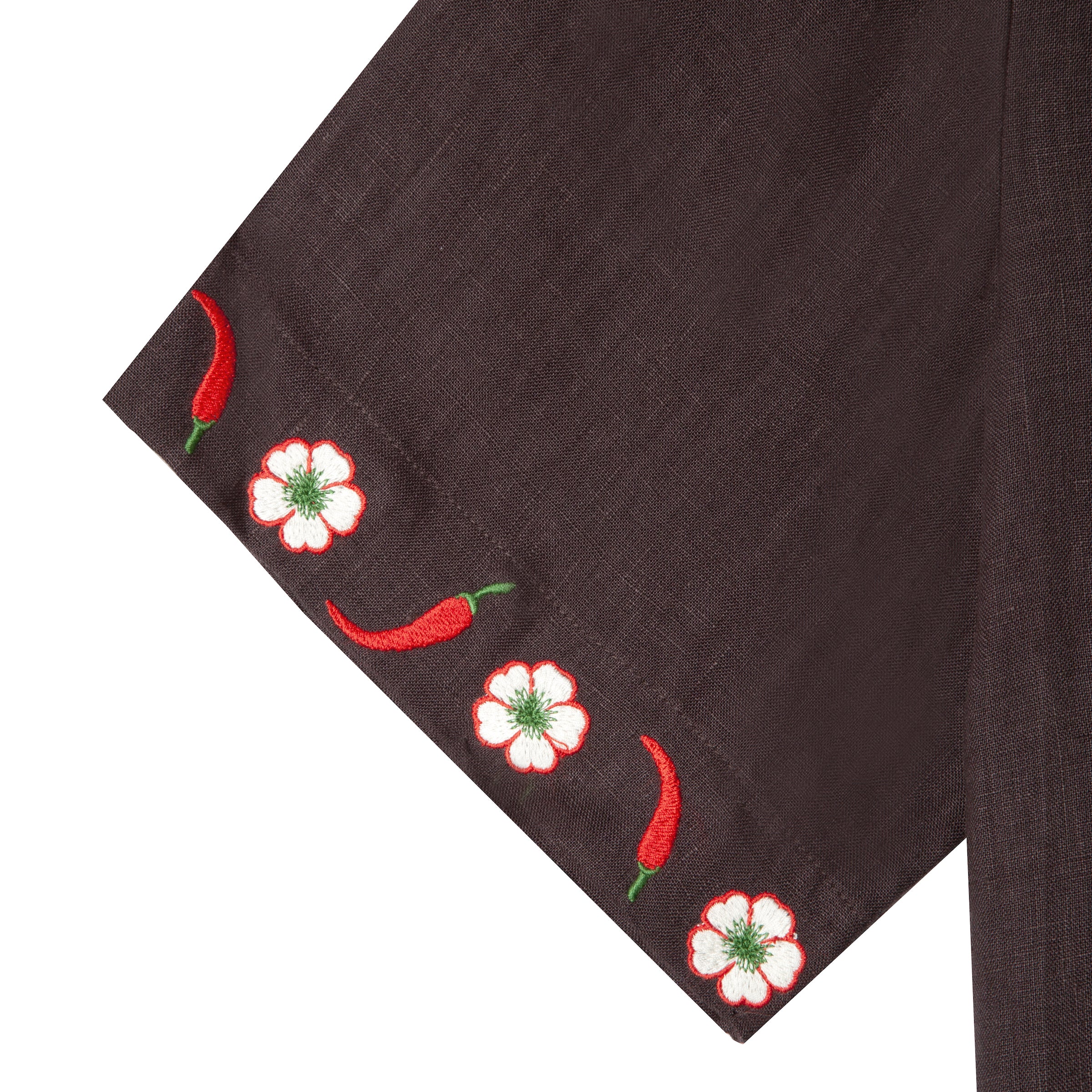 Close up shot of embroidered white flowers and red chili peppers along border of cuff. 
