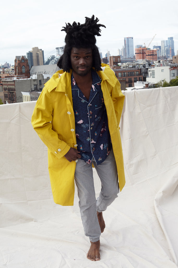 male model wearing shirt on rooftop under a yellow jacket