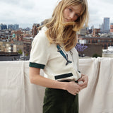 Female model wearing the shirt on a rooftop with green corduroy pants